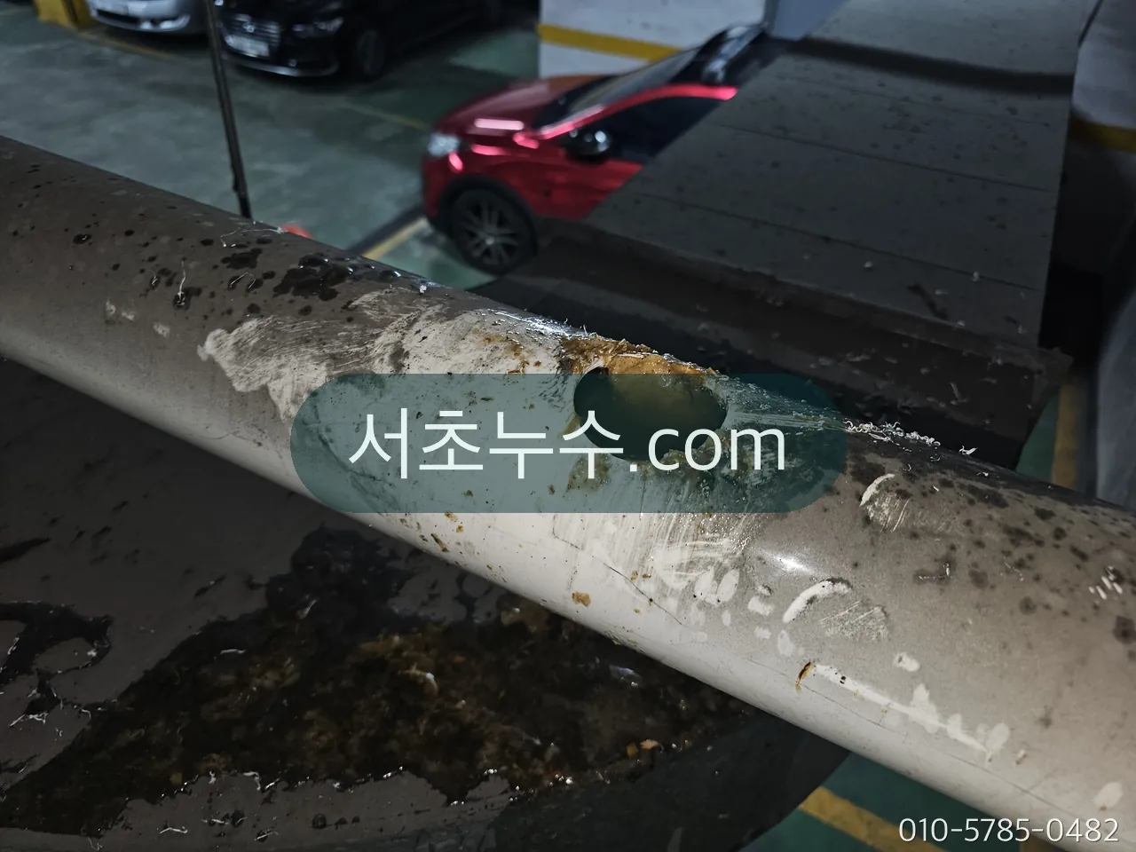 지하주차장 천장 배관의 구멍과 이음부 — 물이 떨어지는 지점 바로 위를 확인하는 장면