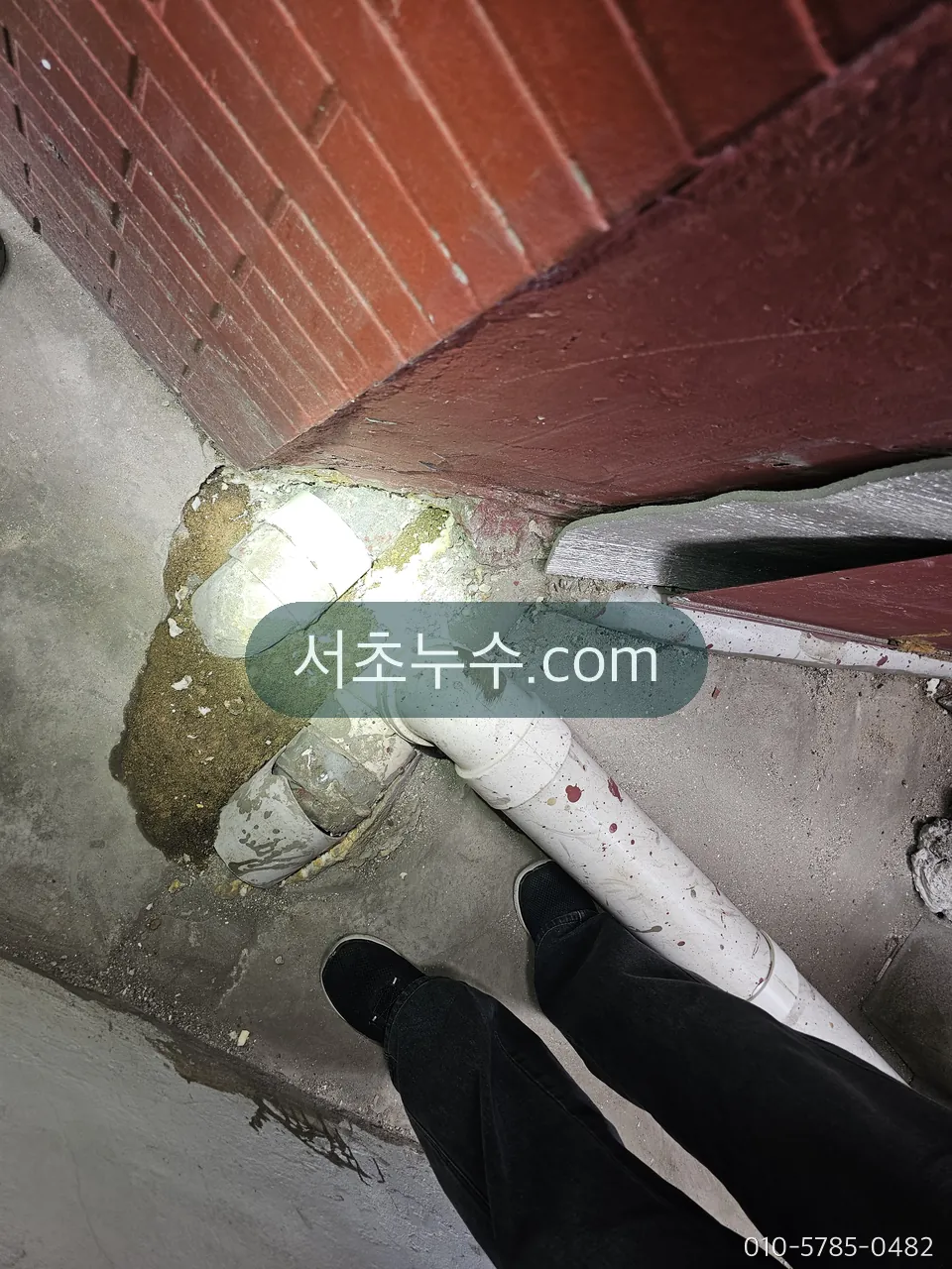벽체 안 배관 연결부를 조명으로 확인하는 모습