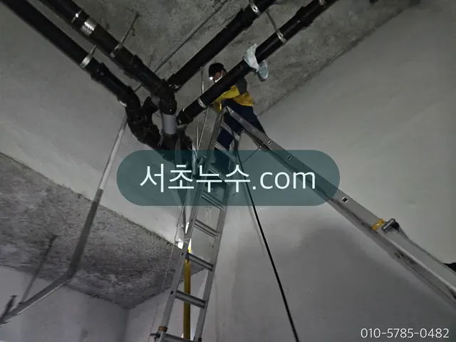 건물 천장 배관을 사다리로 점검하는 작업