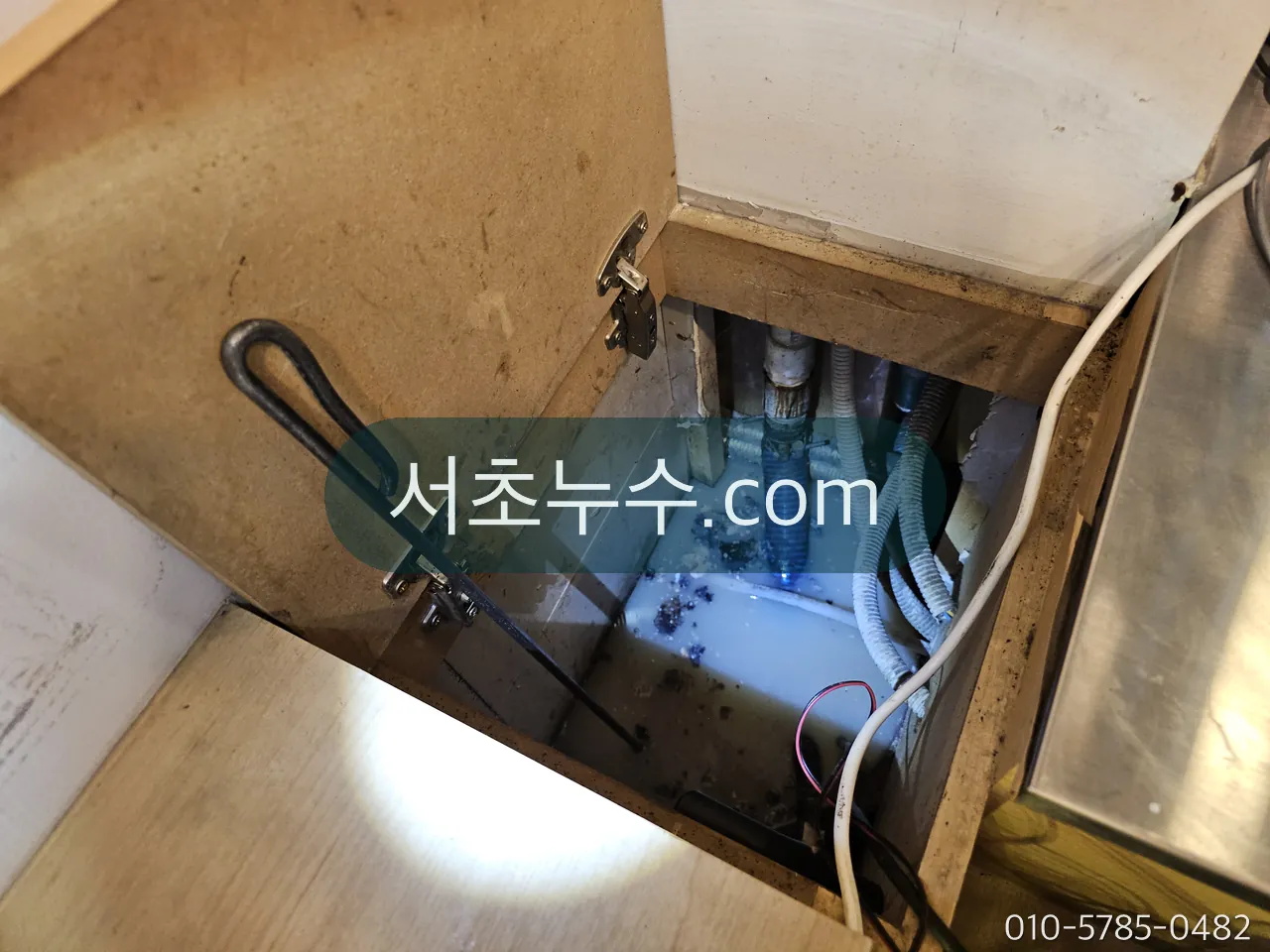 하부장 안 앵글밸브와 연결 호스를 휴대폰으로 촬영해 기록하는 모습